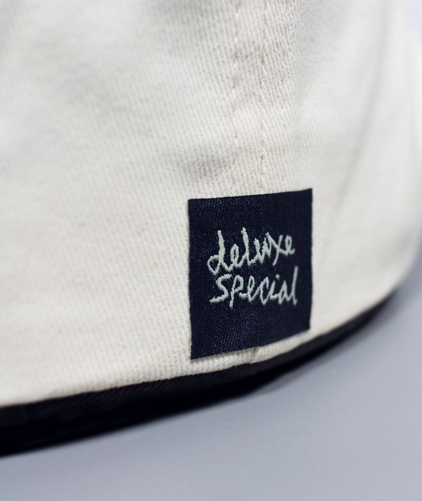 Close-up of a white garment with a black label featuring 'Deluxe Special' text.