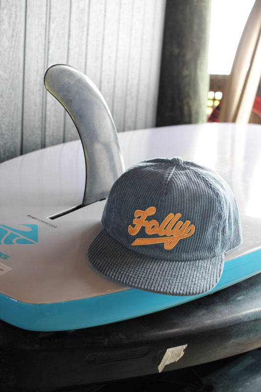 Blue cap with 'Folly' logo on a surfboard