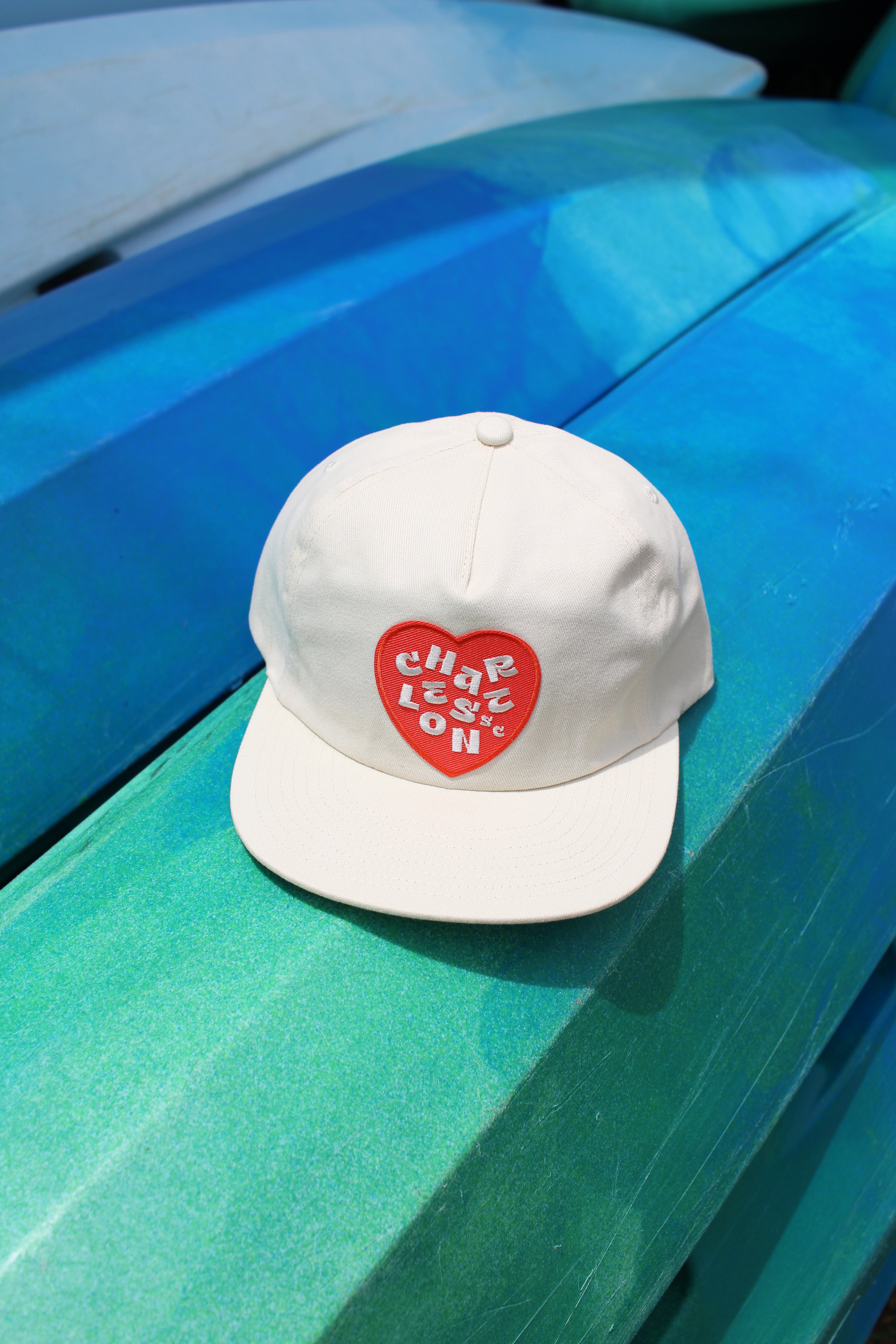 Charleston hat. White cap with a red heart design on a blue surface