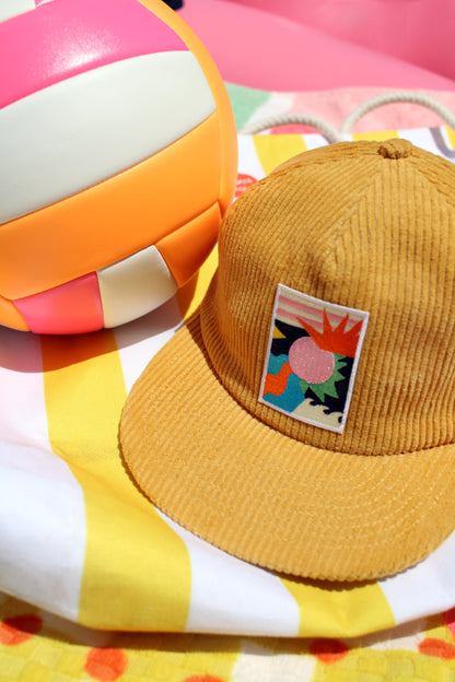 Yellow cap with a colorful patch on a striped pool float with a beach ball in the background
