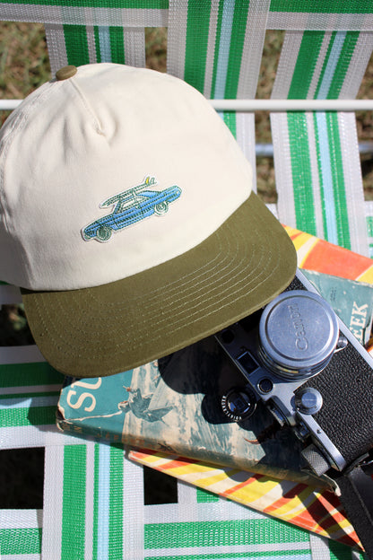 Hat with a vintage car surfboard design on a chair with a camera and colorful object