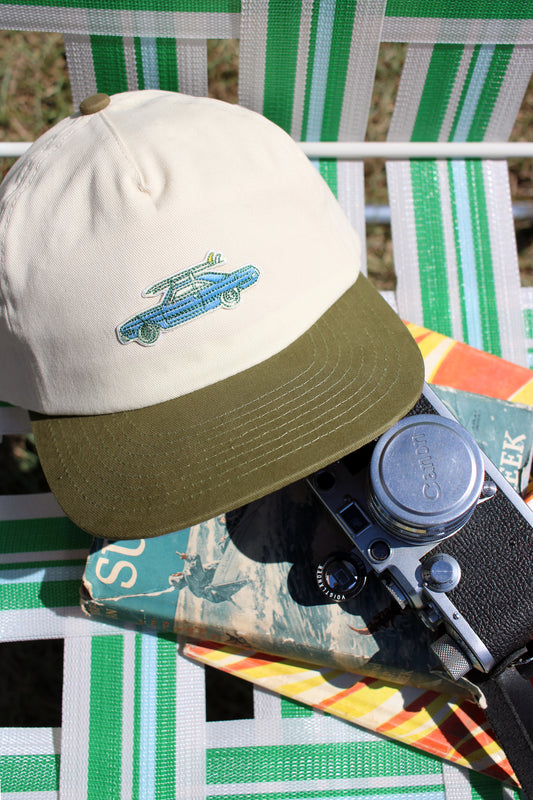Hat with a vintage car surfboard design on a chair with a camera and colorful object