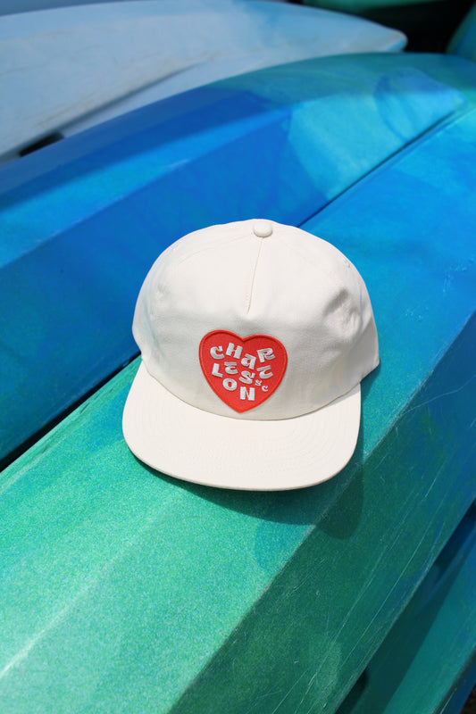 Charleston hat. White cap with a red heart design on a blue surface