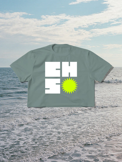 Green t-shirt with 'CHS' design on a beach with ocean and sky background
