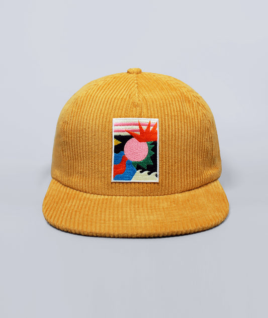 Yellow corduroy cap with a colorful patch on a light gray background