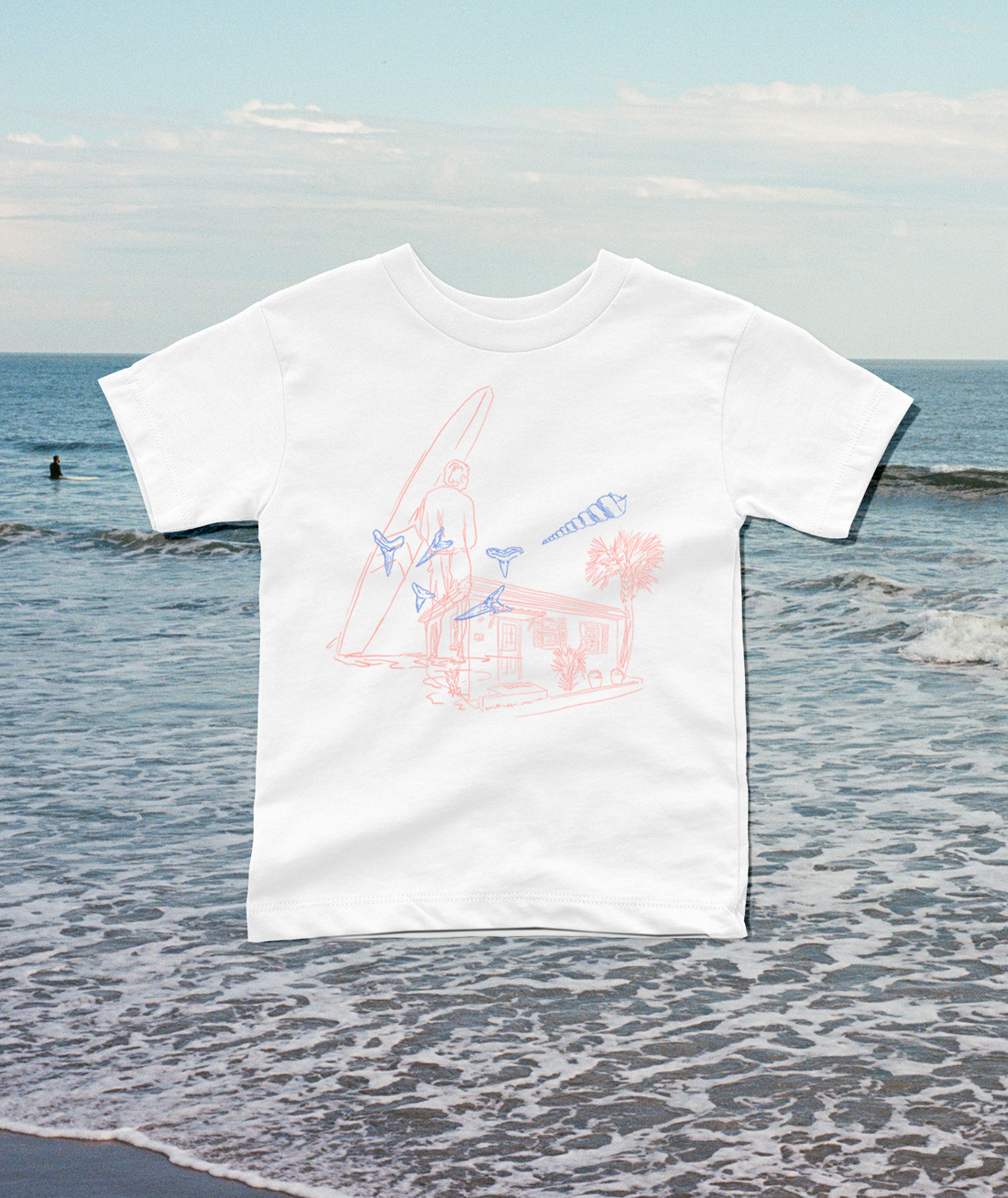 A white short-sleeve t-shirt with a light pink and blue line art graphic of a surfer and beach cabana, displayed against a blurred beach background.