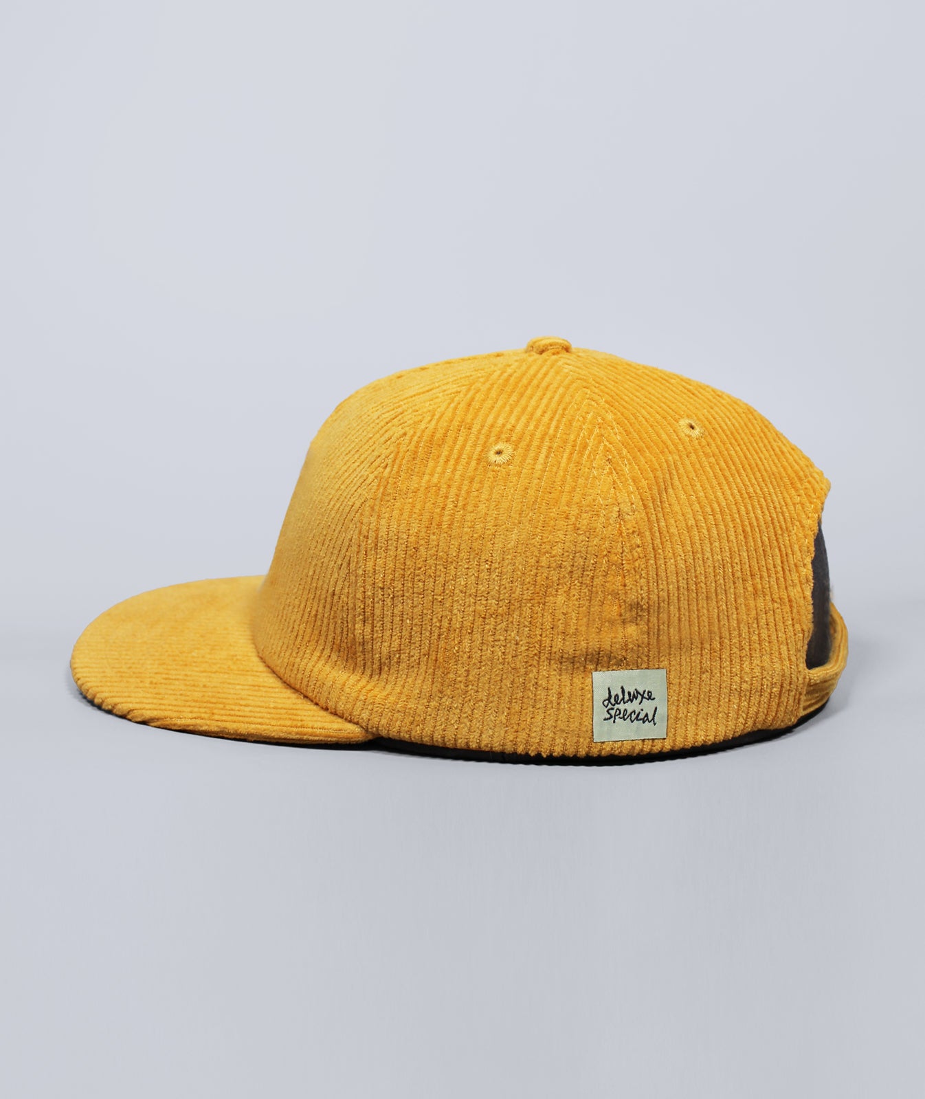 Yellow corduroy cap with a brand label on a gray background